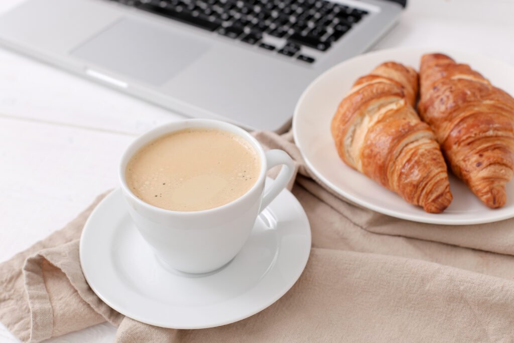 breakfast with croissants coffee near laptop scaled